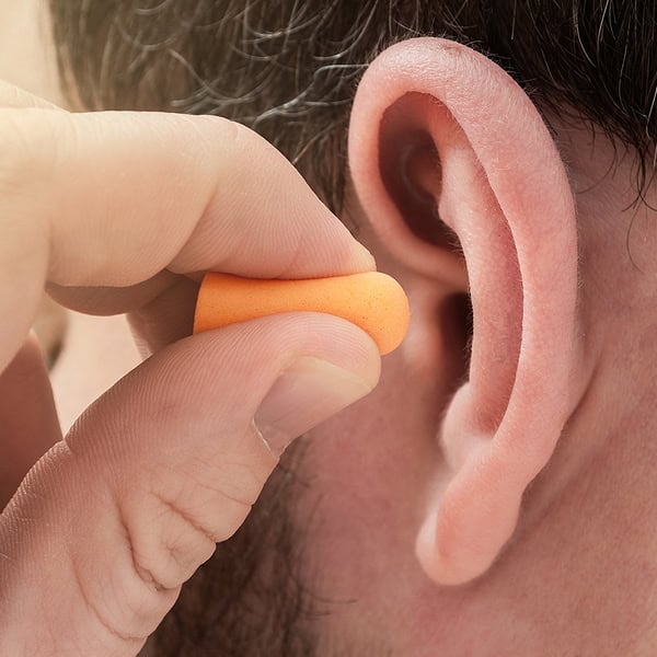 Man Putting Earplugs In Ear