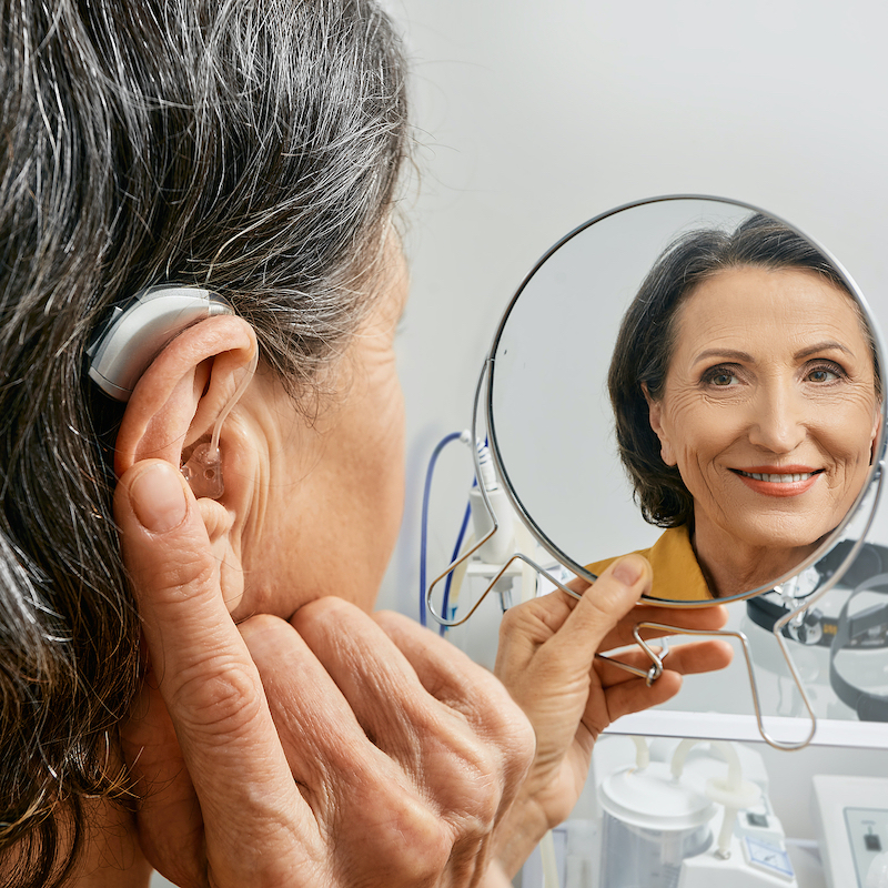 Woman With BTE Hearing Aid Looking in Mirror